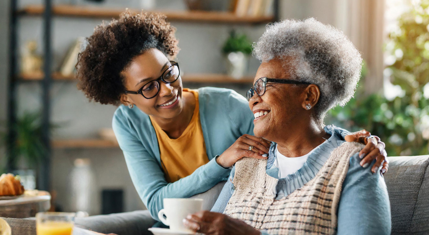 Smiling caregiver hugging an elderly woman at home, reflecting compassionate senior care and personal support.